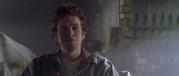 Movie still from “Flickering Lights” (2000), directed by Anders Thomas Jensen – A man with curly brown hair is sitting in a room; Close Up shot, Over the shoulder angle