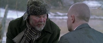 Movie still from “Flickering Lights” (2000), directed by Anders Thomas Jensen – An older man wearing a hat and a jacket talking to a younger man; Close Up shot, Over the shoulder angle