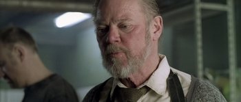 Movie still from “Flickering Lights” (2000), directed by Anders Thomas Jensen – An older man with a beard and a tie; Close Up shot, Low angle