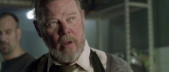 Movie still from “Flickering Lights” (2000), directed by Anders Thomas Jensen – An older man with a beard and a mustache; Close Up shot, Low angle