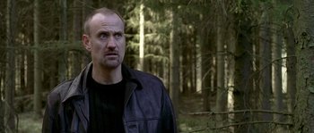 Movie still from “Flickering Lights” (2000), directed by Anders Thomas Jensen – A man standing in the middle of a forest; Close Up shot, Low angle