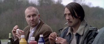 Movie still from “Flickering Lights” (2000), directed by Anders Thomas Jensen – Two men sitting next to each other smoking and drinking; Close Up shot, Over the shoulder angle