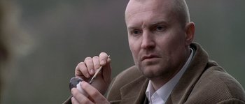 Movie still from “Flickering Lights” (2000), directed by Anders Thomas Jensen – A man holding a pen in his hand and looking at the camera; Close Up shot, Low angle