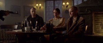 Movie still from “Flickering Lights” (2000), directed by Anders Thomas Jensen – A group of men sitting at a table with bottles of beer; Medium shot, Low angle