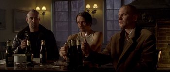 Movie still from “Flickering Lights” (2000), directed by Anders Thomas Jensen – A group of people sitting at a table with beer; Medium shot, Low angle