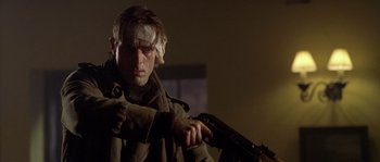 Movie still from “Flickering Lights” (2000), directed by Anders Thomas Jensen – A man with a bandage on his head holding a gun; Close Up shot, Low angle