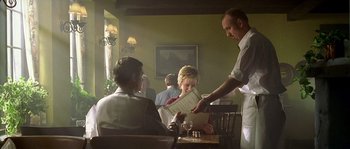 Movie still from “Flickering Lights” (2000), directed by Anders Thomas Jensen – A man is handing a menu to a woman at a restaurant; Medium shot, Low angle