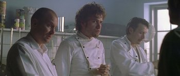 Movie still from “Flickering Lights” (2000), directed by Anders Thomas Jensen – A group of people wearing chef's uniforms in a kitchen; Medium shot, Low angle