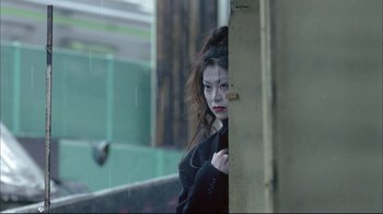 A woman with a black jacket standing next to a wooden door