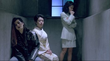 Two women in white suits in a dark room