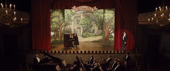 Movie still from “Florence Foster Jenkins” (2016), directed by Stephen Frears – A scene of a stage with a man sitting at a piano; Extreme Wide shot, High angle