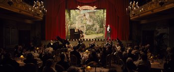 Movie still from “Florence Foster Jenkins” (2016), directed by Stephen Frears – An orchestra performing on a stage in front of an audience; Extreme Wide shot, High angle