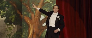 Movie still from “Florence Foster Jenkins” (2016), directed by Stephen Frears – A man in a tuxedo standing in front of a painting; Medium shot, Low angle