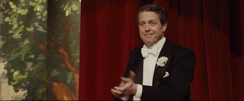 Movie still from “Florence Foster Jenkins” (2016), directed by Stephen Frears – A man in a tuxedo clapping his hands; Medium shot, Over the shoulder angle
