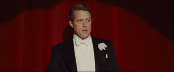 Movie still from “Florence Foster Jenkins” (2016), directed by Stephen Frears – A man in a tuxedo standing in front of a red curtain; Close Up shot, Low angle