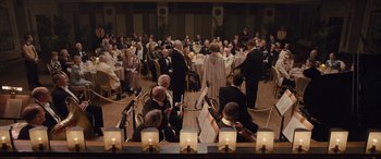 Movie still from “Florence Foster Jenkins” (2016), directed by Stephen Frears – A group of people in a room with candles on the floor; Extreme Wide shot, High angle