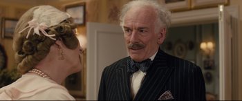 Movie still from “Florence Foster Jenkins” (2016), directed by Stephen Frears – An older man wearing a suit and a bow tie; Close Up shot, Over the shoulder angle
