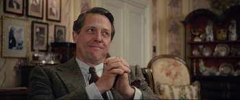 Movie still from “Florence Foster Jenkins” (2016), directed by Stephen Frears – A person sitting in a chair with his hands clasped; Close Up shot, Over the shoulder angle