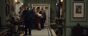 Movie still from “Florence Foster Jenkins” (2016), directed by Stephen Frears – A group of people standing in a room with a dog; Wide shot, Low angle