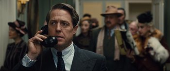 Movie still from “Florence Foster Jenkins” (2016), directed by Stephen Frears – A man in a suit and tie holding a phone to his ear; Close Up shot, Over the shoulder angle
