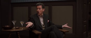 Movie still from “Florence Foster Jenkins” (2016), directed by Stephen Frears – A man sitting in a chair wearing a suit and tie; Medium shot, High angle