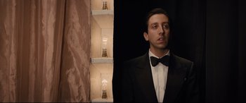 Movie still from “Florence Foster Jenkins” (2016), directed by Stephen Frears – A man in a tuxedo standing in front of a wall; Medium shot, Low angle