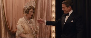 Movie still from “Florence Foster Jenkins” (2016), directed by Stephen Frears – A man and a woman dressed in formal wear; Medium shot, Over the shoulder angle