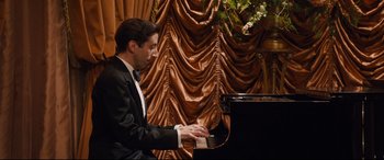Movie still from “Florence Foster Jenkins” (2016), directed by Stephen Frears – A man in a tuxedo playing a piano; Medium shot, Low angle