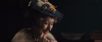 Movie still from “Florence Foster Jenkins” (2016), directed by Stephen Frears – An older woman wearing a black hat with flowers on it's brim; Close Up shot, Over the shoulder angle