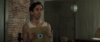 Movie still from “Florence Foster Jenkins” (2016), directed by Stephen Frears – A man holding a brown paper bag with a record on it; Close Up shot, Low angle