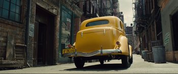 Movie still from “Florence Foster Jenkins” (2016), directed by Stephen Frears – An old car parked on the side of the street; Wide shot, Low angle