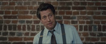 Movie still from “Florence Foster Jenkins” (2016), directed by Stephen Frears – A person wearing suspenders near a brick wall; Close Up shot, Over the shoulder angle