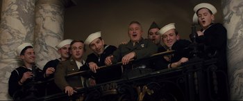 Movie still from “Florence Foster Jenkins” (2016), directed by Stephen Frears – A group of men in military uniforms standing next to each other on a railing; Medium shot, Low angle