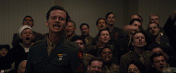 Movie still from “Florence Foster Jenkins” (2016), directed by Stephen Frears – A group of men in military uniforms singing together; Medium shot, Low angle