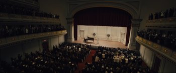 Movie still from “Florence Foster Jenkins” (2016), directed by Stephen Frears – An audience is sitting in front of a stage with a grand piano on it; Extreme Wide shot, High angle