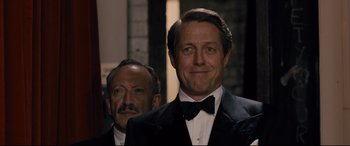 Movie still from “Florence Foster Jenkins” (2016), directed by Stephen Frears – A man in a suit and tie standing next to another man in a suit and tie; Close Up shot, Over the shoulder angle