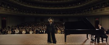 Movie still from “Florence Foster Jenkins” (2016), directed by Stephen Frears – A woman standing in front of an audience and a piano; Extreme Wide shot, High angle