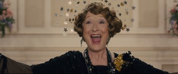 Movie still from “Florence Foster Jenkins” (2016), directed by Stephen Frears – An older woman wearing a black dress and a gold necklace; Close Up shot, Low angle