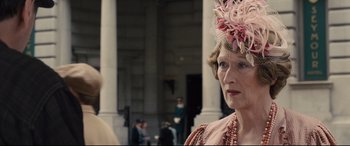 Movie still from “Florence Foster Jenkins” (2016), directed by Stephen Frears – An older woman wearing a pink dress and a pink hat; Close Up shot, Over the shoulder angle