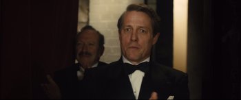 Movie still from “Florence Foster Jenkins” (2016), directed by Stephen Frears – A man in a tuxedo standing next to another man in a suit; Close Up shot, Over the shoulder angle