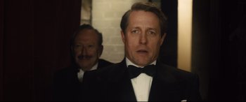 Movie still from “Florence Foster Jenkins” (2016), directed by Stephen Frears – A man in a tuxedo standing next to another man in a suit; Close Up shot, Over the shoulder angle