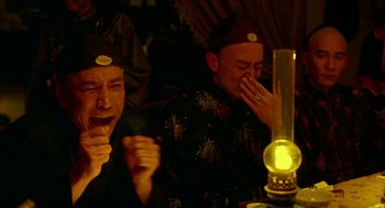 Movie still from “Flowers of Shanghai” (1998), directed by Hsiao-Hsien Hou – Two men sitting in front of a table with a lamp; Medium shot, Low angle