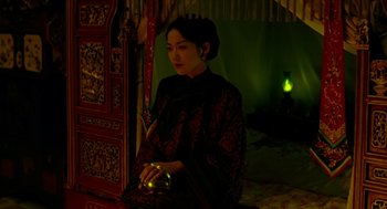 Movie still from “Flowers of Shanghai” (1998), directed by Hsiao-Hsien Hou – A woman sitting on a bed holding a candle; Medium shot, High angle