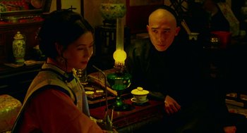 Movie still from “Flowers of Shanghai” (1998), directed by Hsiao-Hsien Hou – A man and a woman sitting at a table with an oil lamp; Medium shot, Over the shoulder angle
