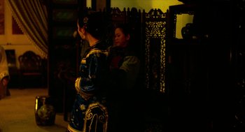 Movie still from “Flowers of Shanghai” (1998), directed by Hsiao-Hsien Hou – A woman standing next to another woman in front of a wooden screen; Medium shot, Over the shoulder angle