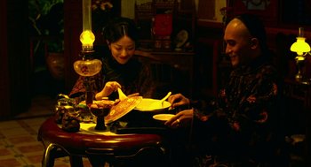 Movie still from “Flowers of Shanghai” (1998), directed by Hsiao-Hsien Hou – A man and a woman sitting at a dinner table; Medium shot, Low angle