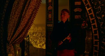 Movie still from “Flowers of Shanghai” (1998), directed by Hsiao-Hsien Hou – A man holding a knife in a room; Medium shot, Low angle