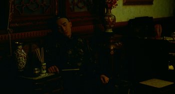 Movie still from “Flowers of Shanghai” (1998), directed by Hsiao-Hsien Hou – A man sitting at a table in a dark room; Medium shot, High angle