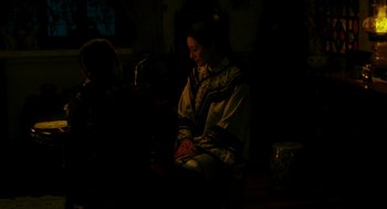 Movie still from “Flowers of Shanghai” (1998), directed by Hsiao-Hsien Hou – A woman sitting on a chair in a dark room; Medium shot, High angle