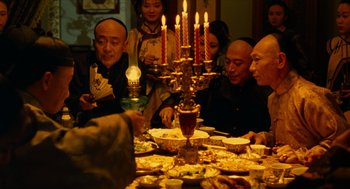 Movie still from “Flowers of Shanghai” (1998), directed by Hsiao-Hsien Hou – A group of people sitting around a dinner table; Medium shot, High angle